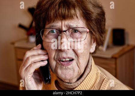 Senior à la maison tandis que le téléphone semble effrayé, petit-fils tour, Cologne, Rhénanie-du-Nord-Westphalie, Allemagne Banque D'Images