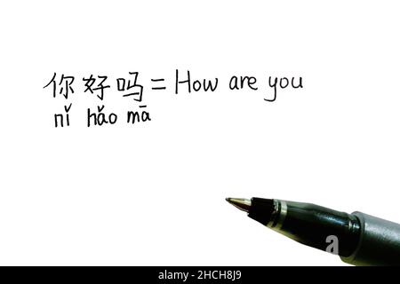 Des caractères chinois manuscrits avec Pinyin de 'How are You' et sa traduction anglaise avec un stylo Banque D'Images