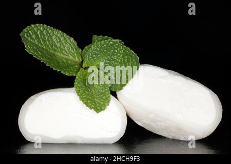 Mochi de moitié (gâteau à base de farine de glace gluante) et menthe, rempli de glace à la noix de coco, photographie en studio avec fond noir Banque D'Images