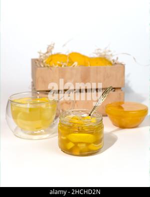 Pot en verre avec confiture de yuzu près d'une boîte en bois avec des fruits yuzu d'agrumes jaunes. yuja-cheong est une marmelade à base de zeste de yuzu, de jus de fruits et de miel. Banque D'Images