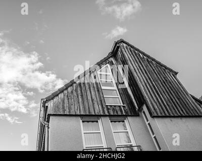 Prise de vue en niveaux de gris à faible angle d'une maison moderne en bois contre un ciel nuageux Banque D'Images