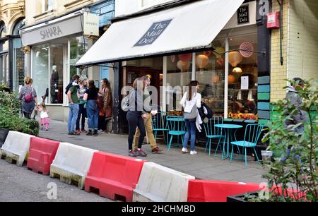 Magasins, restaurants le long de la galerie marchande étant piétonnes avec des jardinières et manger le long de la route avec des tables et des chaises, Clifton, Bristol Banque D'Images