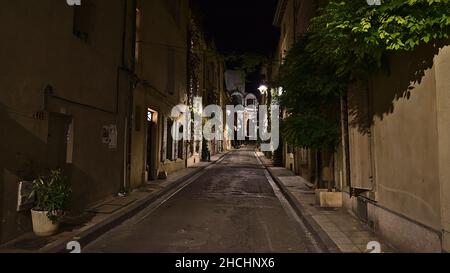 Vue de nuit avec une perspective décroissante d'une ruelle étroite dans le centre historique d'Arles, Provence, France avec le célèbre amphithéâtre romain. Banque D'Images