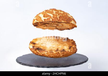 un hamburger bun vide, levant sur un carreau de pierre noir, isolé sur fond blanc.Mise au point sélective Banque D'Images
