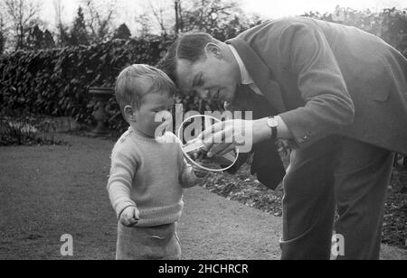 Fin 1950s, historique, à l'extérieur d'un jardin, un père montrant à son jeune fils comment utiliser son jouet portatif, Angleterre, Royaume-Uni. Banque D'Images