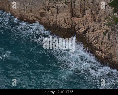 Vue de haut angle avec vagues de la mer Méditerranée agitée se brisant sur les falaises abruptes de la chaîne de montagnes massif des Calanques près de Cassis, Côte d'Azur. Banque D'Images