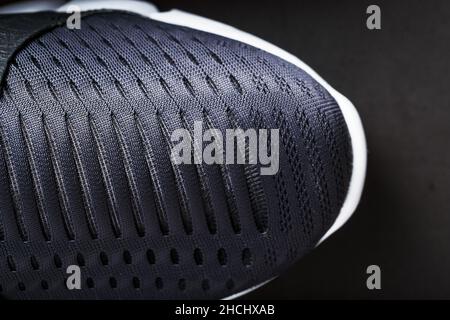 Chaussures de course à pied avec mesh et semelles noires et blanches en gros plan sur fond sombre.Vue de dessus des baskets de sport. Banque D'Images