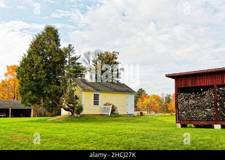 La maison d'abeilles jaune et le bassin de bois rouge contre les arbres d'automne lors d'un jour d'automne couvert.Canterbury Shaker Village, New Hampshire États-Unis. Banque D'Images