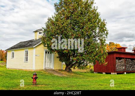 La maison d'abeilles jaune et le bassin de bois rouge contre les arbres d'automne lors d'un jour d'automne couvert.Canterbury Shaker Village, New Hampshire États-Unis. Banque D'Images