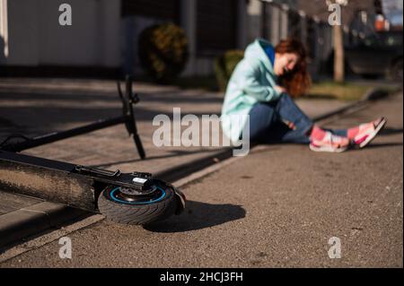 Une femme de race blanche est tombée d'un scooter électrique et a blessé sa jambe.Souffrant de douleur. Banque D'Images