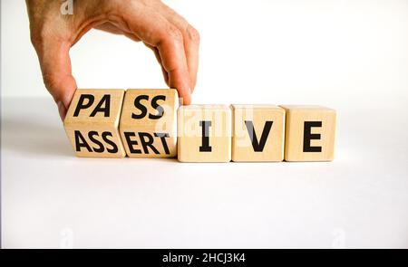 Symbole passif ou assertif.L'homme d'affaires tourne des cubes de bois et change le mot passif à l'assertif.Magnifique arrière-plan blanc, espace de copie.Affaires Banque D'Images