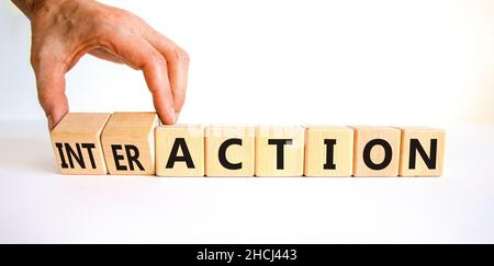 Symbole d'action ou d'interaction.Homme d'affaires tourne des cubes en bois et change le mot action en interaction.Beau tableau blanc fond blanc, copie Banque D'Images