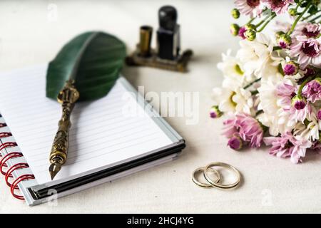 Mariage ou d'engagement sonne avec un vieux stylo et un bloc-notes pour écrire une note.De belles fleurs accompagnent la composition. Banque D'Images