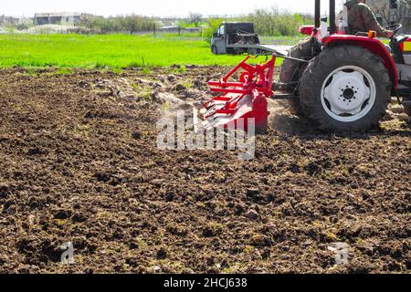 Un tracteur plte la terre dans un terrain de jardin le jour du printemps.Agriculture et agronomie. Banque D'Images