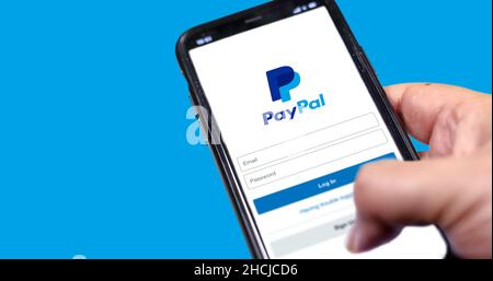 Rome, Italie, le 16 février 2021: Main tenant un smartphone avec page de connexion de l'application Paypal à l'écran et logo Paypal flou en arrière-plan. Transfert d'argent Banque D'Images