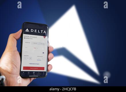 Atlanta, États-Unis, octobre 2021 : main tenant un téléphone avec l'application de réservation de vol Delta Airlines.Logo Delta flou sur fond bleu.Delta Airlin Banque D'Images