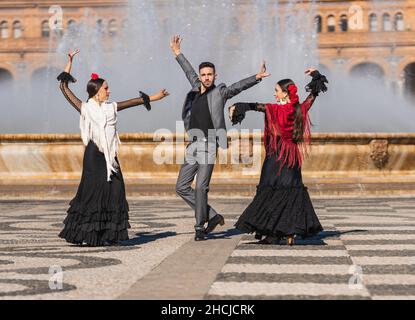 Trois personnes dansant en costume de flamenco sur une place traditionnelle Banque D'Images