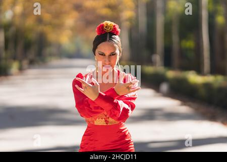 Danseuse de flamenco en robe rouge avec des œillets sur sa tête dansant à l'extérieur Banque D'Images