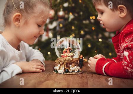 Enfants regardant une boule de verre avec une scène de la naissance de Jésus-Christ Banque D'Images