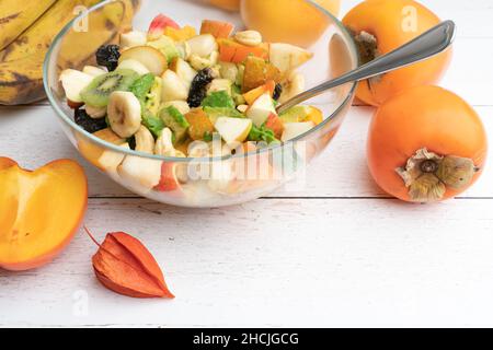 Studio avec bol en verre et salade de fruits fraîchement préparée sur une table en bois blanc.Concept de saine alimentation.Plats végétariens.Régime végétalien brut Banque D'Images