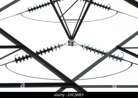 Photographie regardant à l'intérieur à travers une grande tour de transmission électrique en acier contre un ciel gris nuageux Banque D'Images
