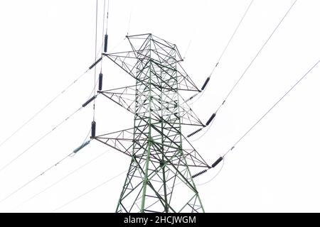 Photographie d'une grande tour de transmission électrique en acier près d'une route de terre dans une forêt contre un ciel gris nuageux Banque D'Images