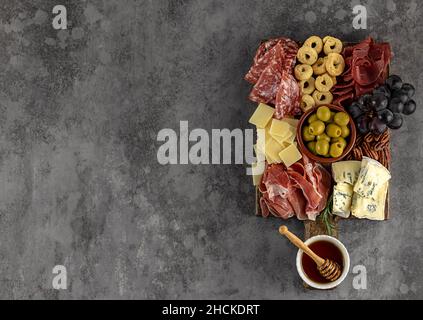 Vue de dessus d'un savoureux plateau de charcuterie avec fromage, raisin, noix, olives et jambon sur une plaque de cuisine circulaire Banque D'Images