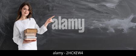 Une jeune fille chargée de cours à l'université près d'un étudiant en tableau noir ou d'un enseignant en classe.Leçon en ligne sur l'appareil photo et la femme pointant avec le doigt à placer pour le texte Banque D'Images