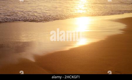 Lumière du coucher du soleil sur les vagues de l'océan.Plage de sable tropical, reflet du coucher de soleil. Banque D'Images