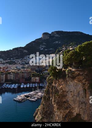 Paysage urbain de Monaco sur la côte méditerranéenne avec des rochers escarpés et célèbre port de plaisance Port de Fontvieille au-dessous des collines rocheuses au soleil de l'après-midi. Banque D'Images