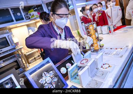 (211230) -- BEIJING, 30 décembre 2021 (Xinhua) -- Un membre de l'équipage expose des souvenirs à thème des Jeux Olympiques d'hiver de Beijing 2022 sur un train du chemin de fer à grande vitesse Beijing-Zhangjiakou le 30 décembre 2021.Le chemin de fer à grande vitesse reliant Pékin et Zhangjiakou dans la province de Hebei, dans le nord de la Chine, est entré en service le 30 décembre 2019.(Xinhua/Huang Zhen) Banque D'Images