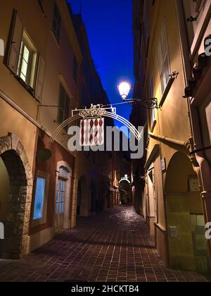 Belle vue nocturne d'une ruelle vide dans le centre historique de Monaco (Monaco-ville) sur la côte méditerranéenne avec vieux bâtiment illuminé. Banque D'Images