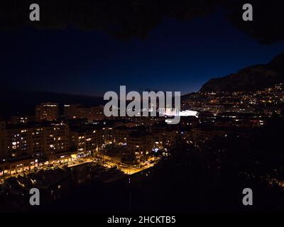 Belle vue nocturne sur le port de plaisance Port de Fontvieille à Monaco sur la Côte d'Azur avec des immeubles modernes et un stade éclairé. Banque D'Images