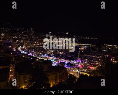 Belle vue panoramique sur le centre-ville illuminé de Monaco la nuit avec foire colorée et port de plaisance Port Hercule entouré de bâtiments. Banque D'Images