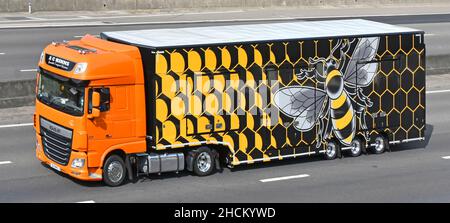 Camion de l'entrepreneur de transport et design graphique impressionnant dans la vue latérale de la remorque avec grande abeille superposée sur fond de nid d'abeille autoroute britannique Banque D'Images