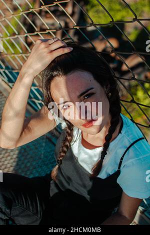 Photo verticale d'une jeune femme hispanique élégante avec deux tresses posant à l'extérieur Banque D'Images