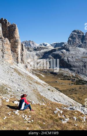 Femme assise en automne dans un pré de montagne qui regarde la vallée de Cengia et les sommets des Dolomites Sexten, Tyrol du Sud, Italie Banque D'Images