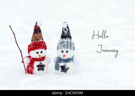 Joyeux noël et bonne année carte de voeux avec espace copie deux petits bonshommes de neige heureux en rouge, bleu casquette et écharpe debout dans la neige d'hiver Banque D'Images