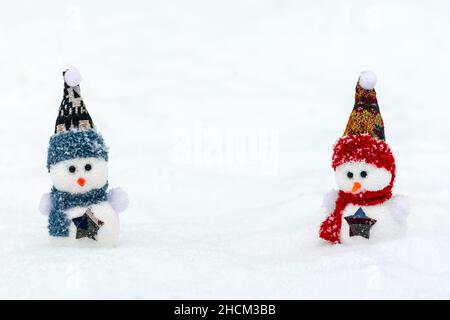 Joyeux noël et bonne année carte de voeux avec espace copie deux petits bonshommes de neige heureux en rouge, bleu casquette et écharpe debout dans la neige d'hiver Banque D'Images