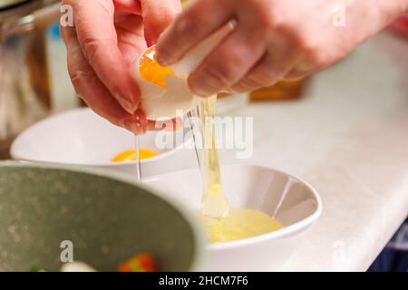 femme caucasienne sérante mains cassant blanc oeuf de poulet au-dessus du bol blanc Banque D'Images