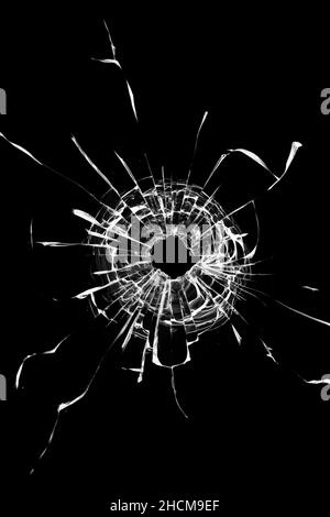 Effet photo de verre brisé, un trou avec des fissures dans le verre sur un fond sombre. Banque D'Images