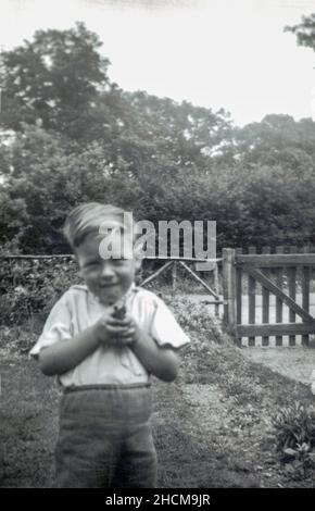 Jeune garçon caucasien âgé de 4 ans jouant dans le jardin avec un fusil à jouets 1956 Banque D'Images