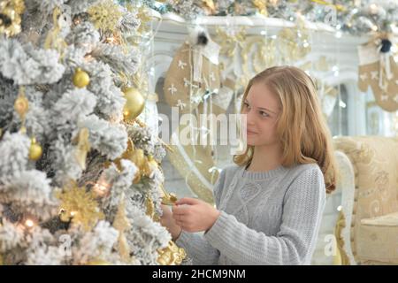 Belle fille décorant arbre de Noël à la maison Banque D'Images