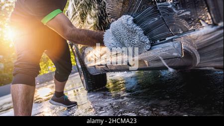 lavage d'une voiture SUV noire avec une éponge sur un lavage de voiture Banque D'Images