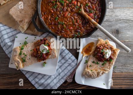 Ragoût de pain. Frais et fait maison, cuits avec des haricots et des légumes. Servi avec du pain plat sur une table en bois. Banque D'Images