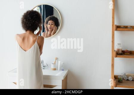 Femme afro-américaine floue appliquant des cellules oculaires dans la salle de bains Banque D'Images