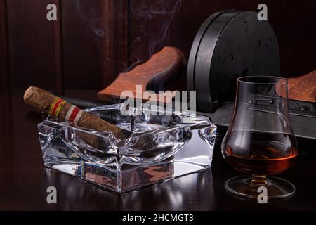 Fusil de sous-machine vintage Thompson sur une table marron foncé avec un cigare et un whisky Banque D'Images