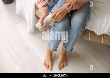 Maman mettant les chaussettes sur son petit fils Banque D'Images