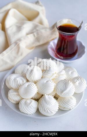 Petites meringues blanches dans un plat blanc.Prise de vue macro.Vue verticale Banque D'Images