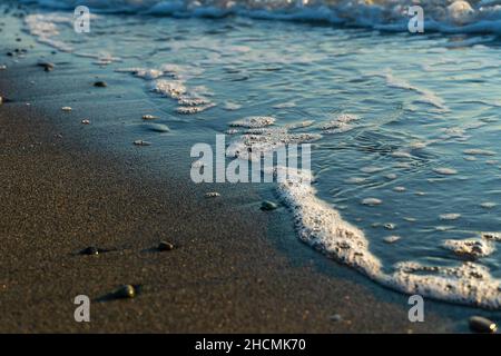Gros plan de sable et de petits cailloux sur la plage sur le fond de la mer et du ciel au coucher du soleil.Magnifique fond de nature Banque D'Images